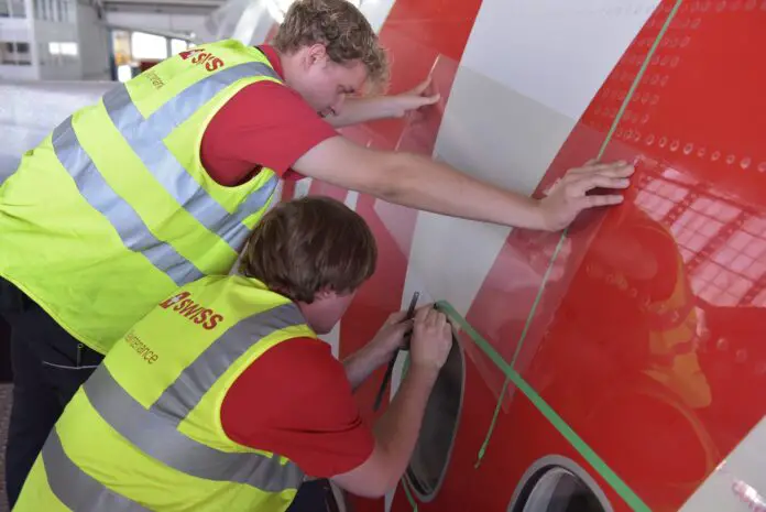 Dos personas aplicando el film aeroshark a un avión de la empresa Swiss